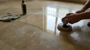 Mani che lucidano un pavimento in marmo opaco con una lucidatrice